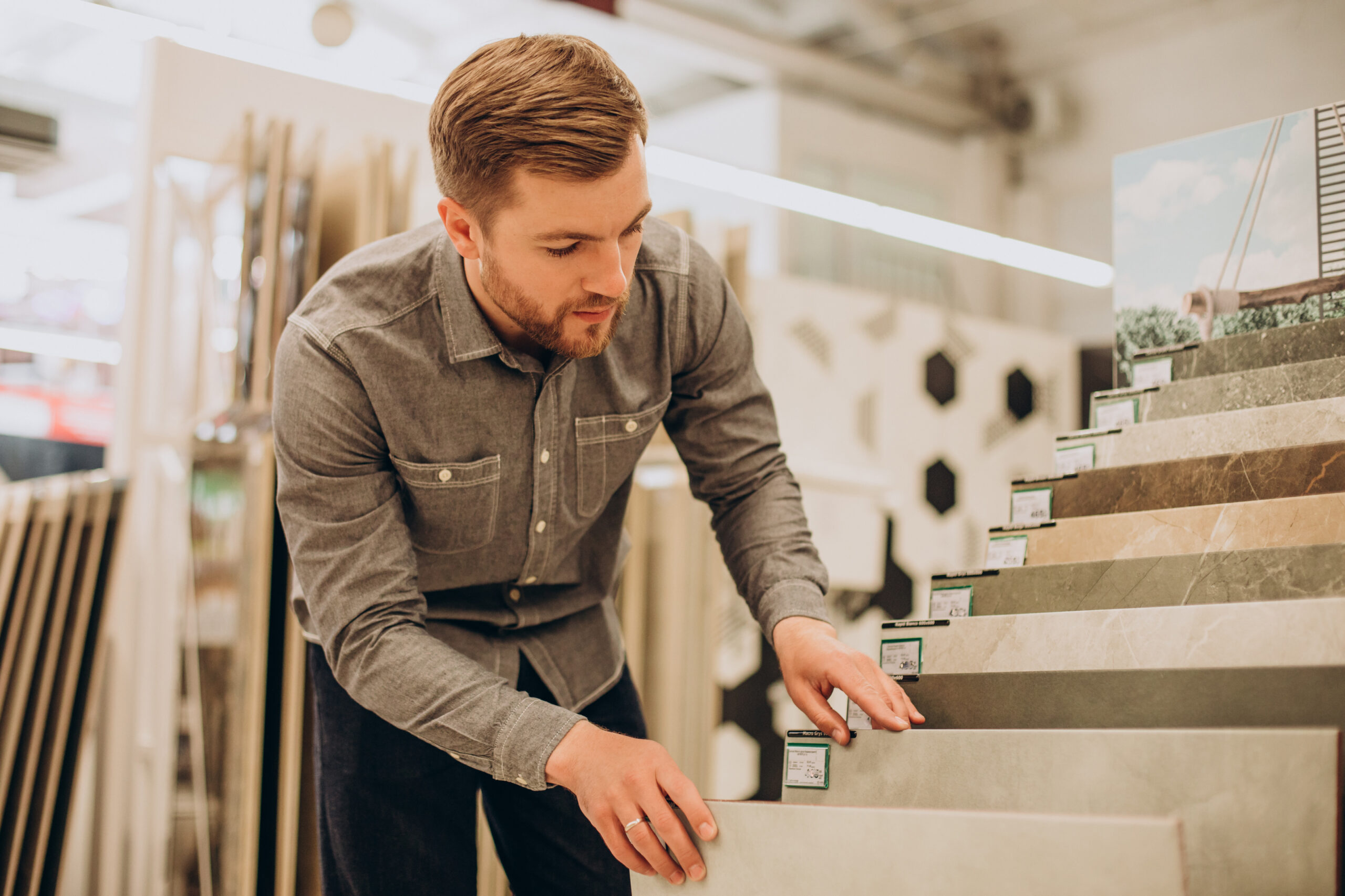 Young man choosing tiles at building market