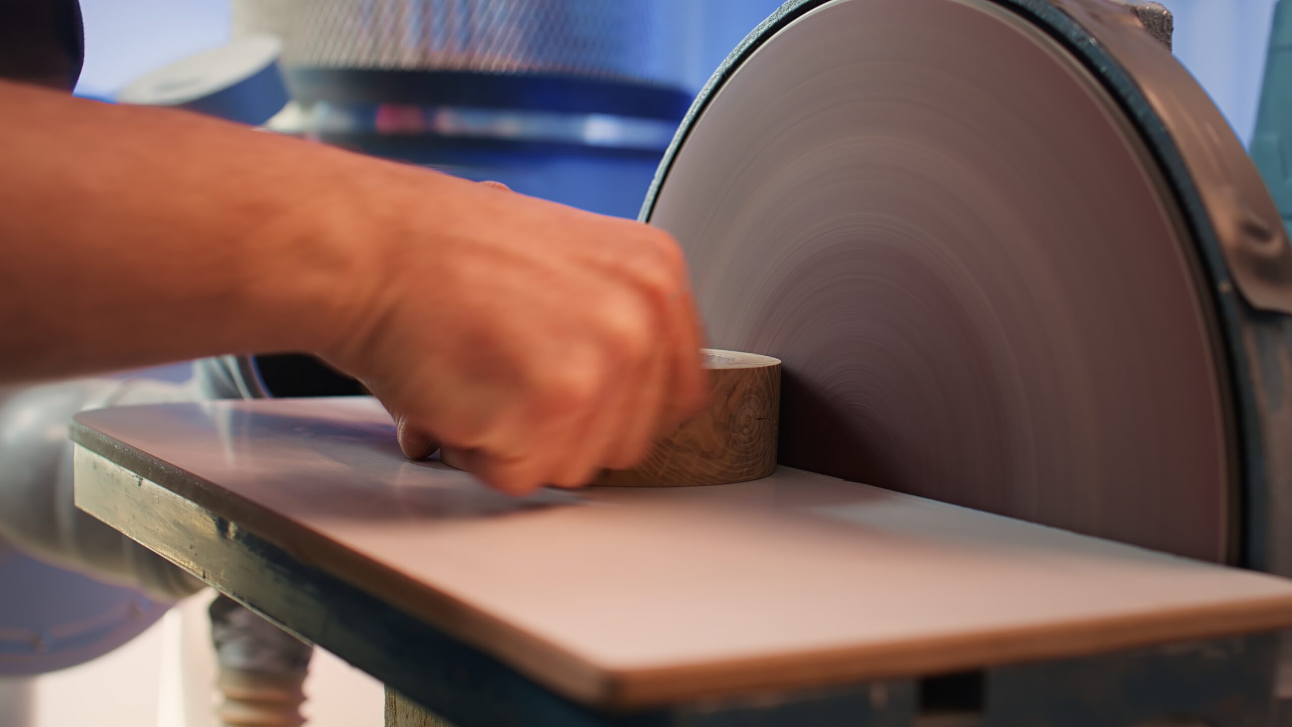 Artisan sanding wooden object on disc sander in assembling shop. Diy hobby enjoyer working in joinery, guiding wood against grinding machine rotating disc to create art, camera B close up shot